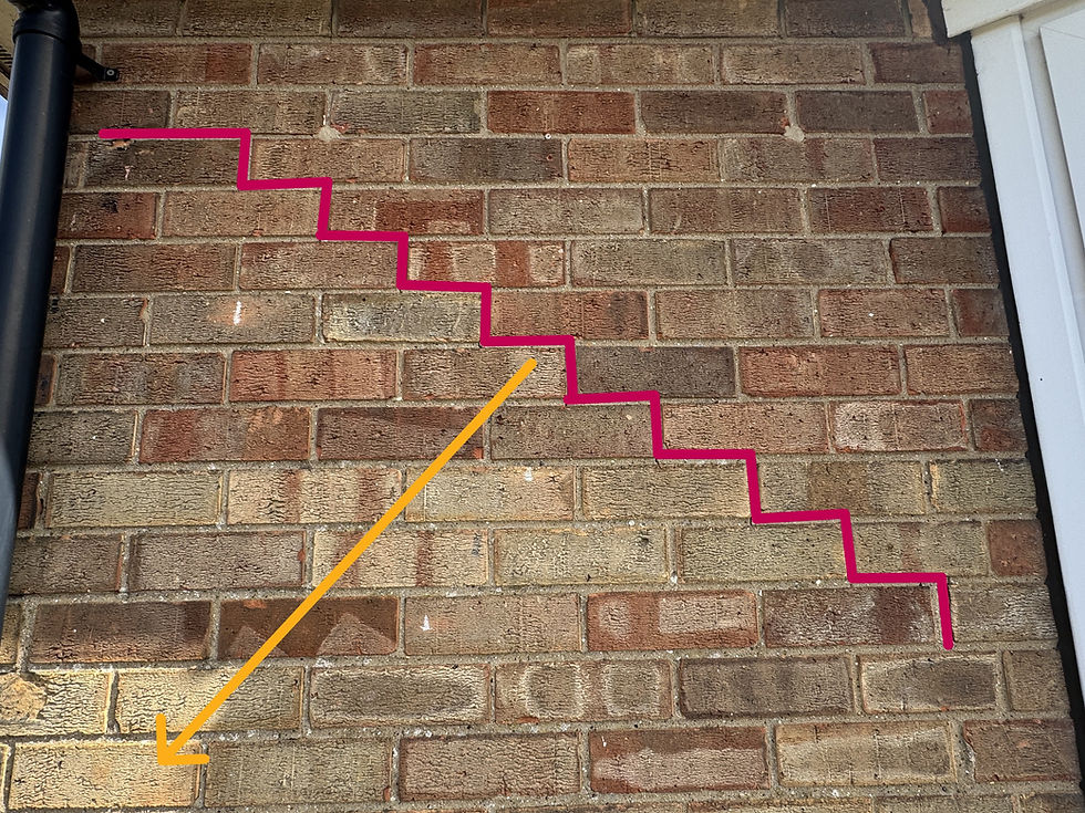 Stepped diagonal cracking to brickwork identified during a building survey in Driffield, East Yorkshire, with the crack traced in red and an arrow showing the direction of movement