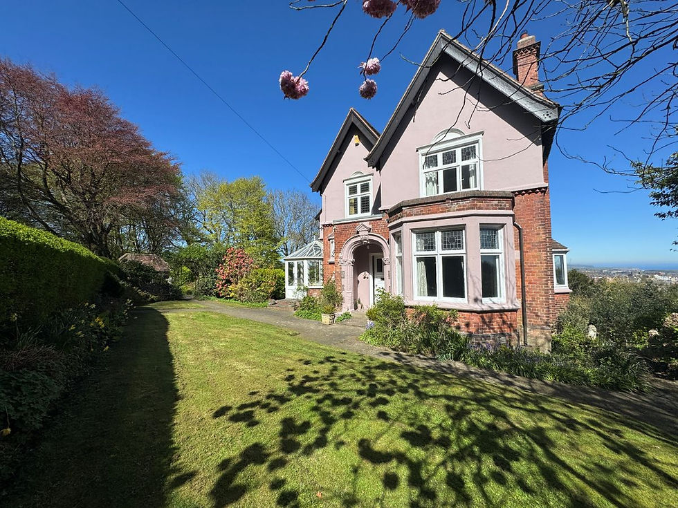 Edwardian detached period home in Scarborough with painted render, red brick lower walls and a clay tiled roof, set in mature gardens