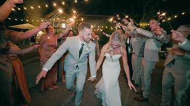 Bride and groom laughing during a sparkler exit at night.