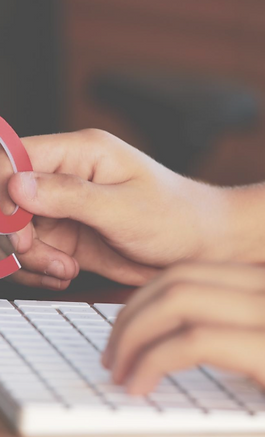 Person typing at a keyboard holding an @ symbol