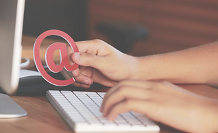 Person typing at a keyboard holding an @ symbol