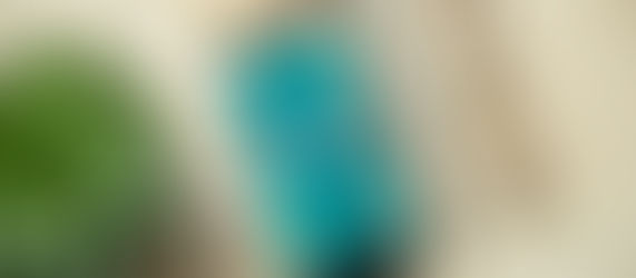 A picture of a phone with a lock screen on a desk with earpods, a pencil, glasses, and a plant.