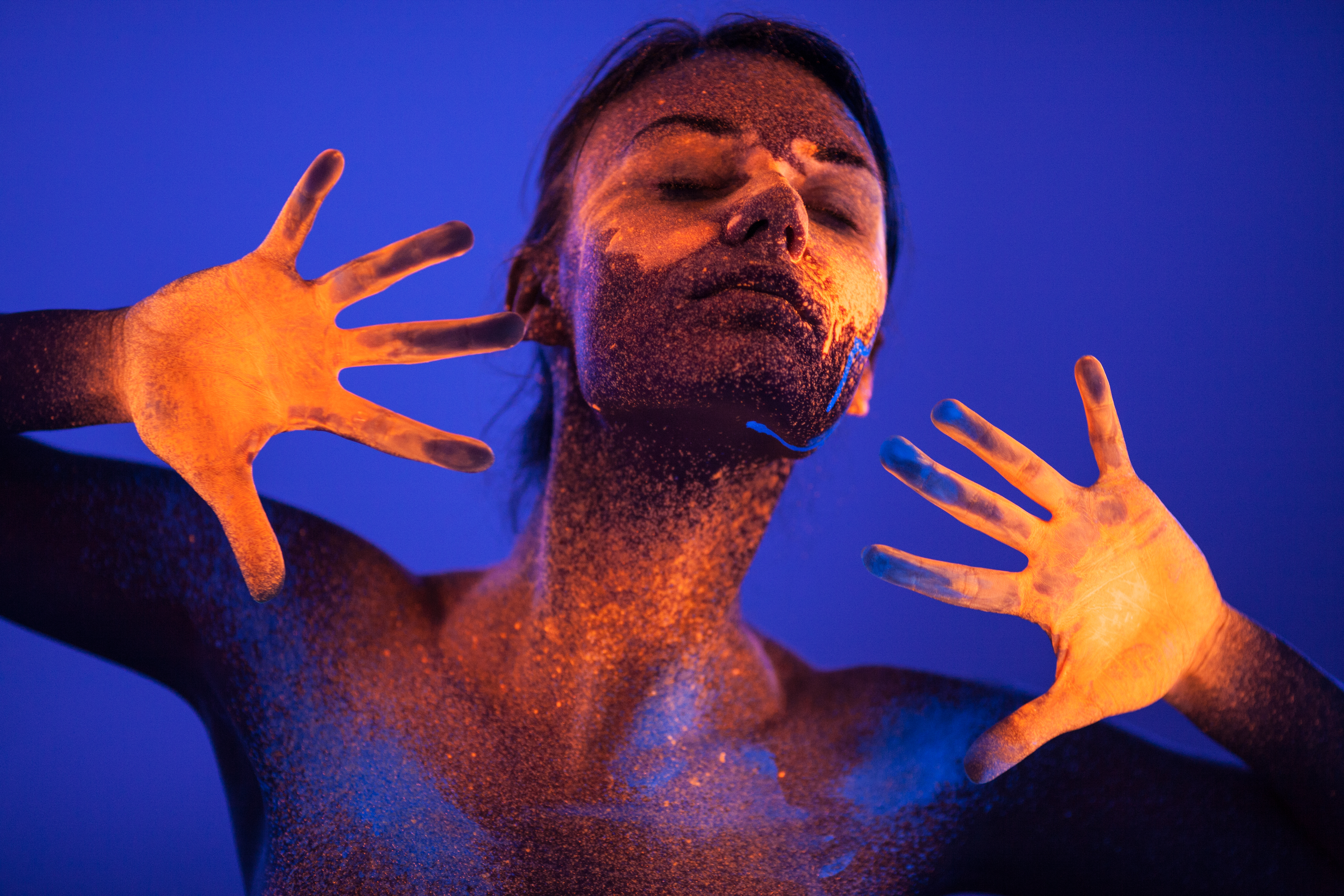 Woman with glowing hands and face in front of a blue background.