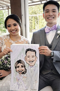 a couple holds their caricatures ata weding at izenstone in spanish fort, AL