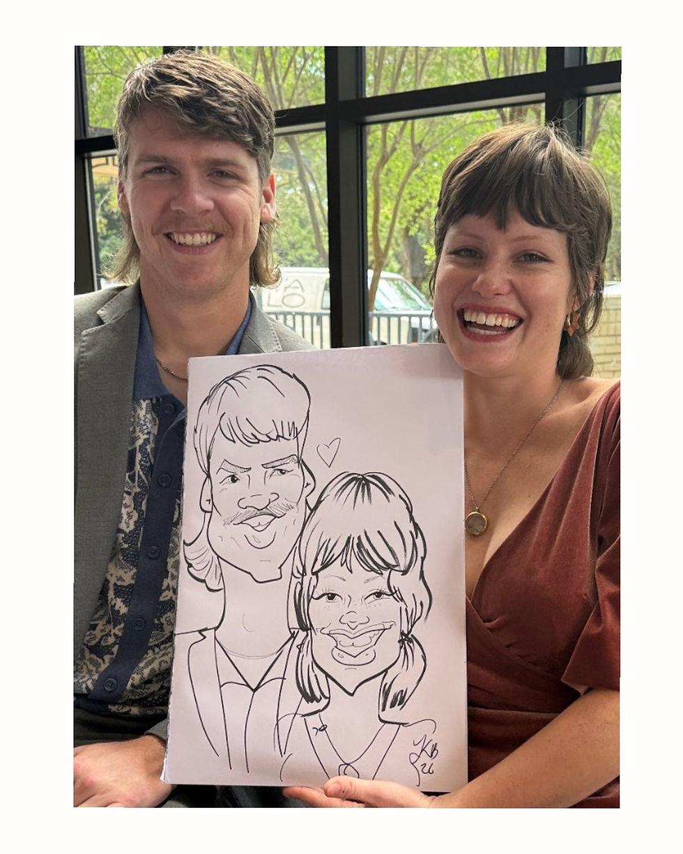 A Couple laughs at their caricatures at a cocktail hour in Pensacola FL at the Cathedral of the Sacred Heart