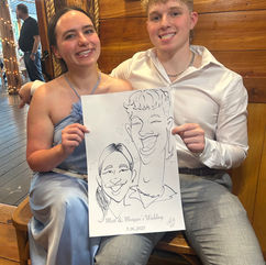 guests hold their wedding caricature by kathy buskett and smile at a wedding at the cedar post barn in Louisiana