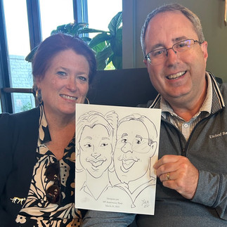 A wife and husband  get a caricature by kathy at the barn at hope farms in Fairhope, AL at mosquito joes tenth anniversary party
