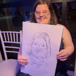 A woman with downs syndrome gets a caricature by caricatures by kathy at an outdoor wedding at the oakes venue in Ponchatoula, LA spring 2025