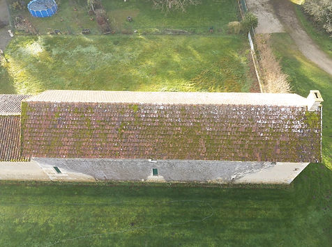 Vue d'une toiture en tuile très sales, et pleine de mousse, avant pulvérisation et traitement anti-mousse par drone, à Montamisé, près de Poitiers dans la Vienne