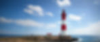 a wide aspect image of a coastal scene with a red and white lighthouse .jpg