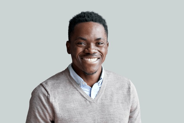 Smiling young Black man in sweater and shirt looking at camera.