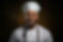 Smiling chef in white uniform and hat. ABOUT Zoi Nomad Restaurant.