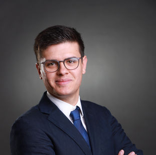 Bewerbungsfoto von einem Mann mit einem dunkelblauen Anzug und grauem Hintergrund
