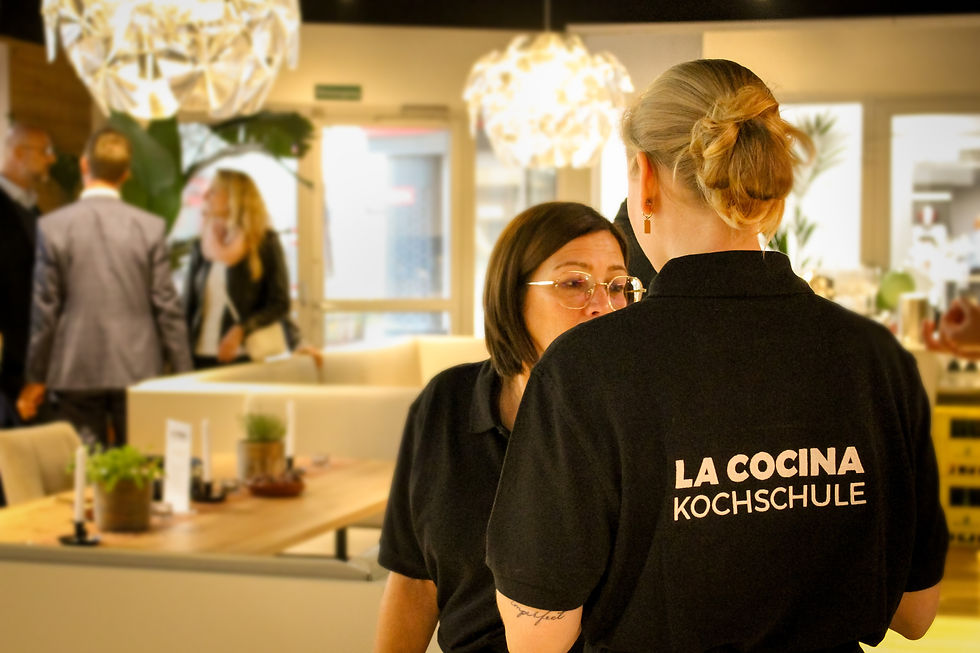 Teamevent Kochen Wien – Kollegen lachen beim Anrichten der Gerichte in der Showküche