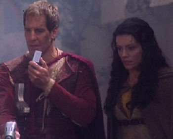 Archer talks into his communicator while Riaan stands next to him.