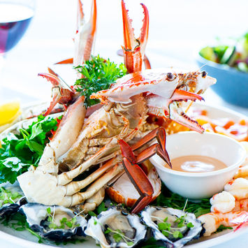 Delicious seafood platter: crab, oysters, prawns, lemon, and sauce