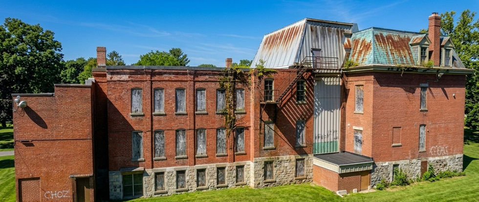 Ancien bâtiment en briques envahi par la végétation.