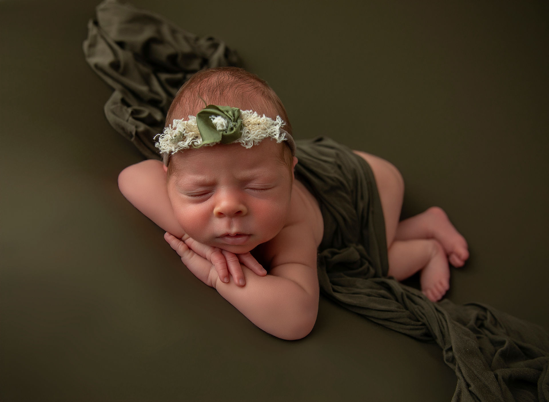 Curled newborn baby photographed in a warm newborn photography studio