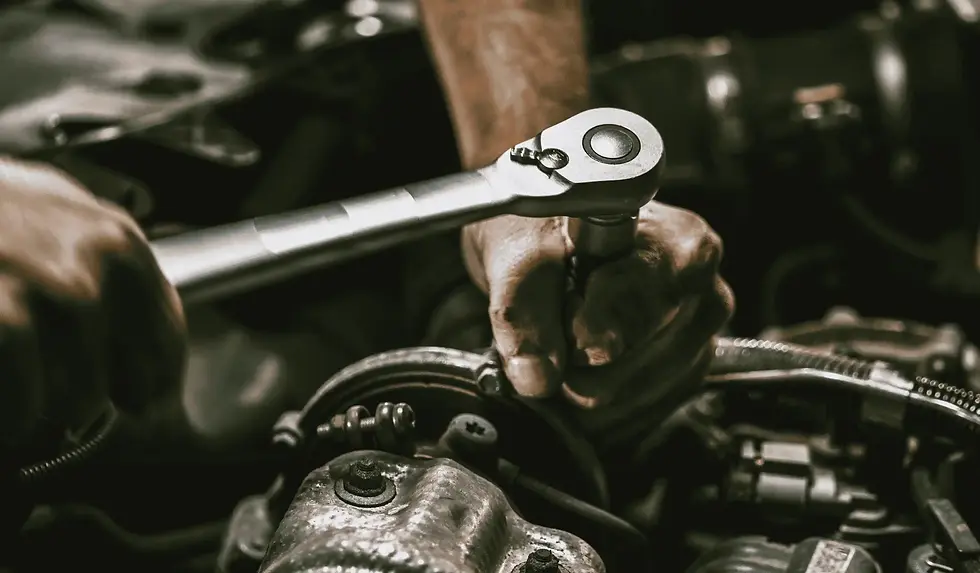 Ein Mann schraubt an dem Motor eines Autos rum