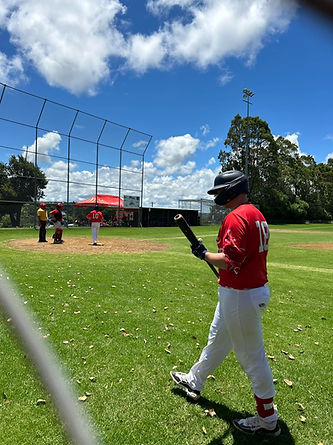 Baseball player in Mudgeeraba uniform walking to up to the plate to bat