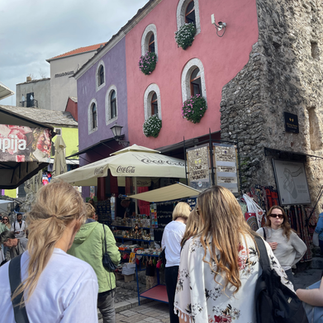 Women walking through street in Mostar with bright pastel colourful buildings
