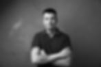 Content Creator mit tätowierten Armen vor grauem Hintergrund