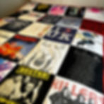 blanket on a bed handmade from concert T-shirts, featuring bands and artists like Busted, Ed Sheeran, and The Killers