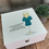 Thumbnail: White wooden box with a champagne glass image dressed in a teal nurses tunic