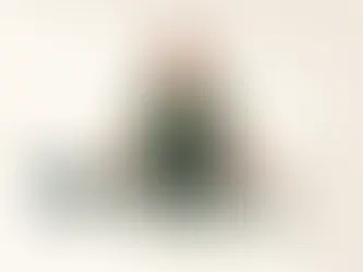 Nuori urheiluvaatteissa istuu salilattian puuparkettilla pelikontrollerin ja juoksukenkien vieressä.