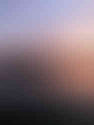 Boats moored on Lake Windermere at sunset with a pink sky and calm water