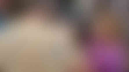 An older man in a tan shirt is fist-bumping a little girl in a purple jacket. The little girl is smiling as she returns the fist bump.