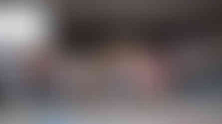 A large group photo of students and volunteers stand on a stage, waving at the camera.