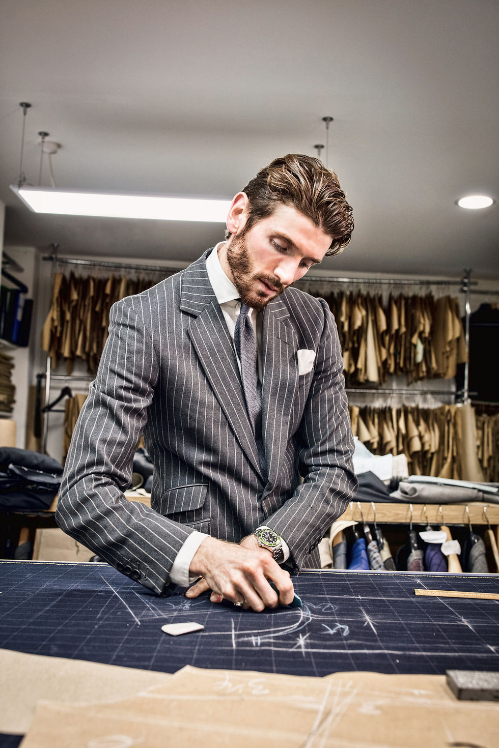 man in pinstripe bespoke suit chalking out a pattern for a bespoke suit pattern