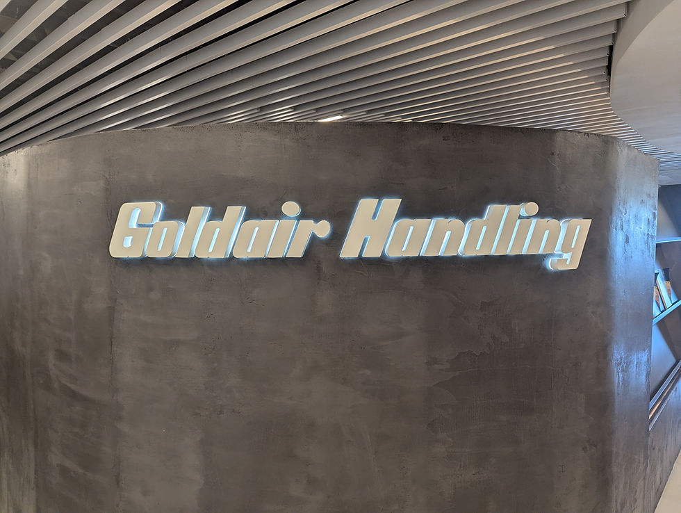 Illuminated "Goldair Handling" sign on a textured gray wall with a slatted ceiling, creating a modern and sleek ambiance at Corfu Airport