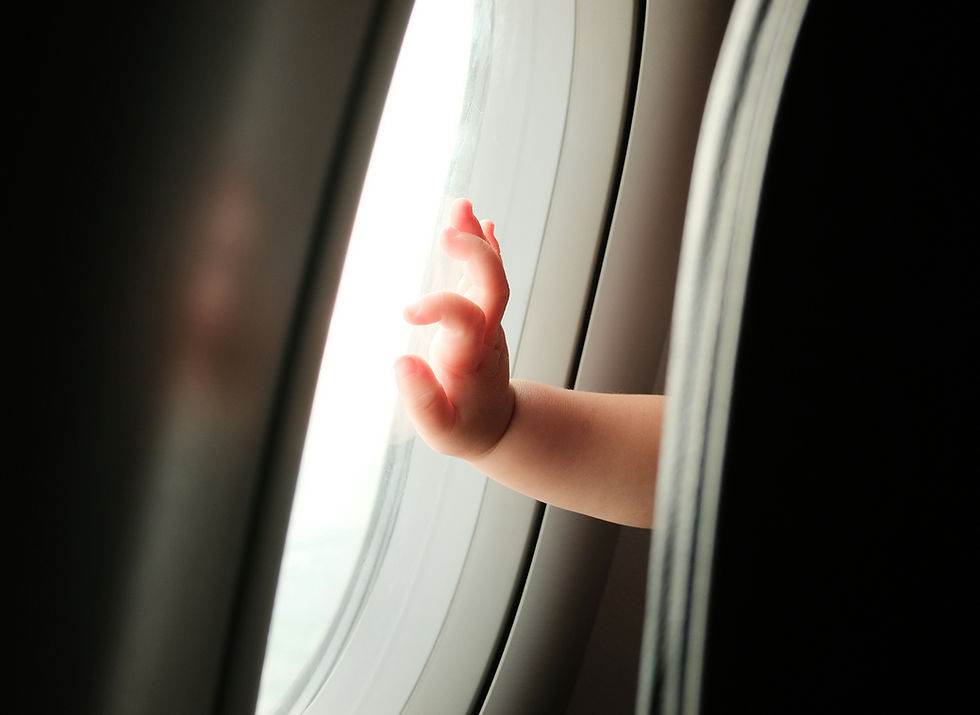 Child's hand touching an airplane window, soft sunlight illuminating the scene. Focus on curiosity and exploration. No visible text. Airliens all have different policies when flying with an under 2