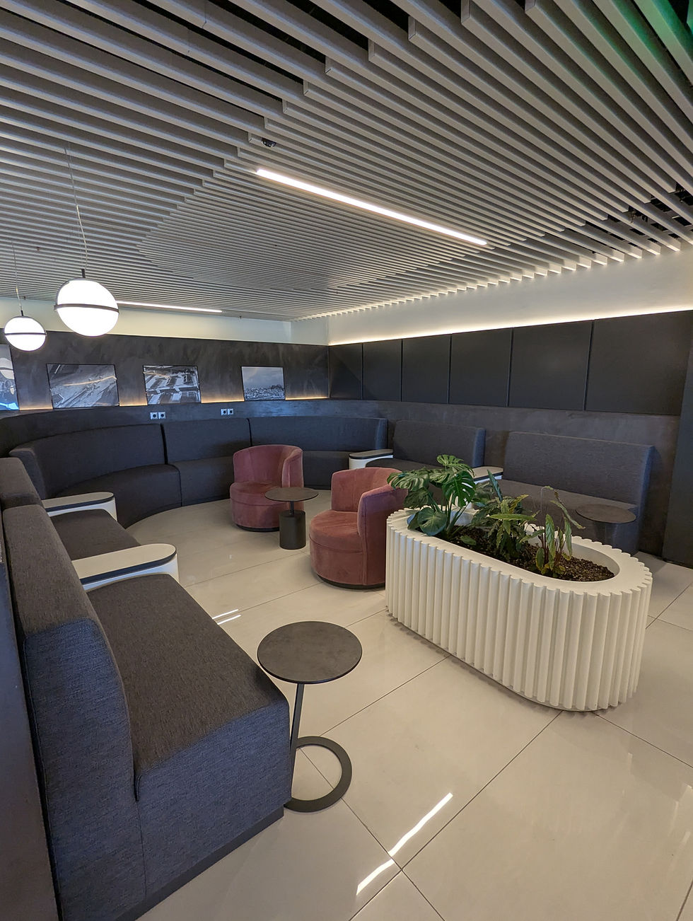 Modern lounge with gray couches, pink chairs, and a white planter, Goldair Handling Lounge Corfu Airport