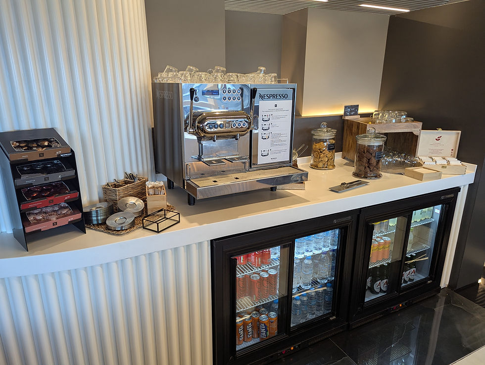Coffee station with a Nespresso machine, cups, snacks, and drinks in a fridge at Goldair Handling Lounge Corfu Airport