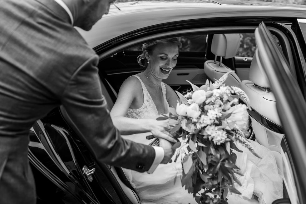 De bruidegom helpt zijn bruid bij het instappen.