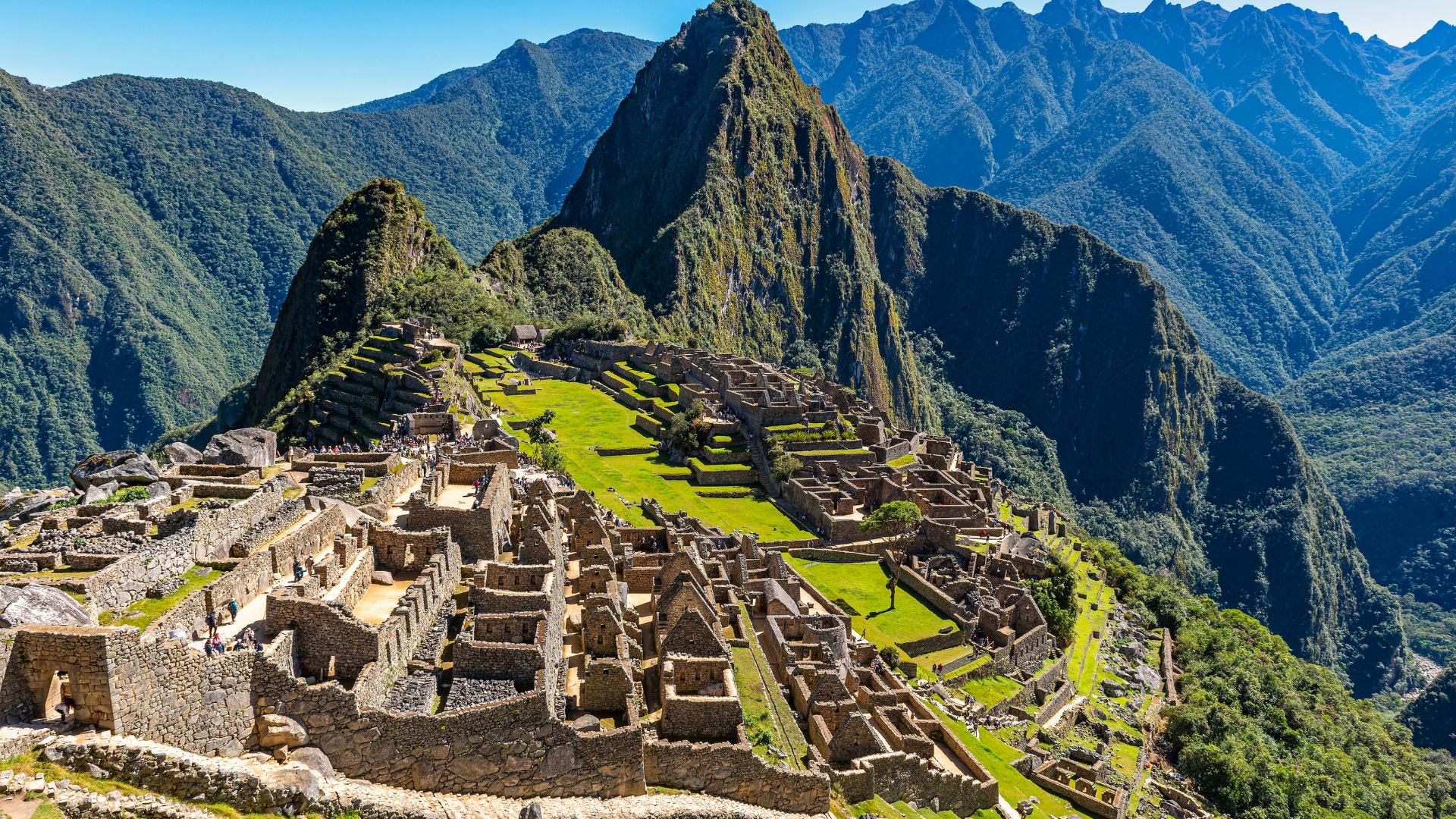 Machu Picchu under a clear sky, with Huayna Picchu rising behind it