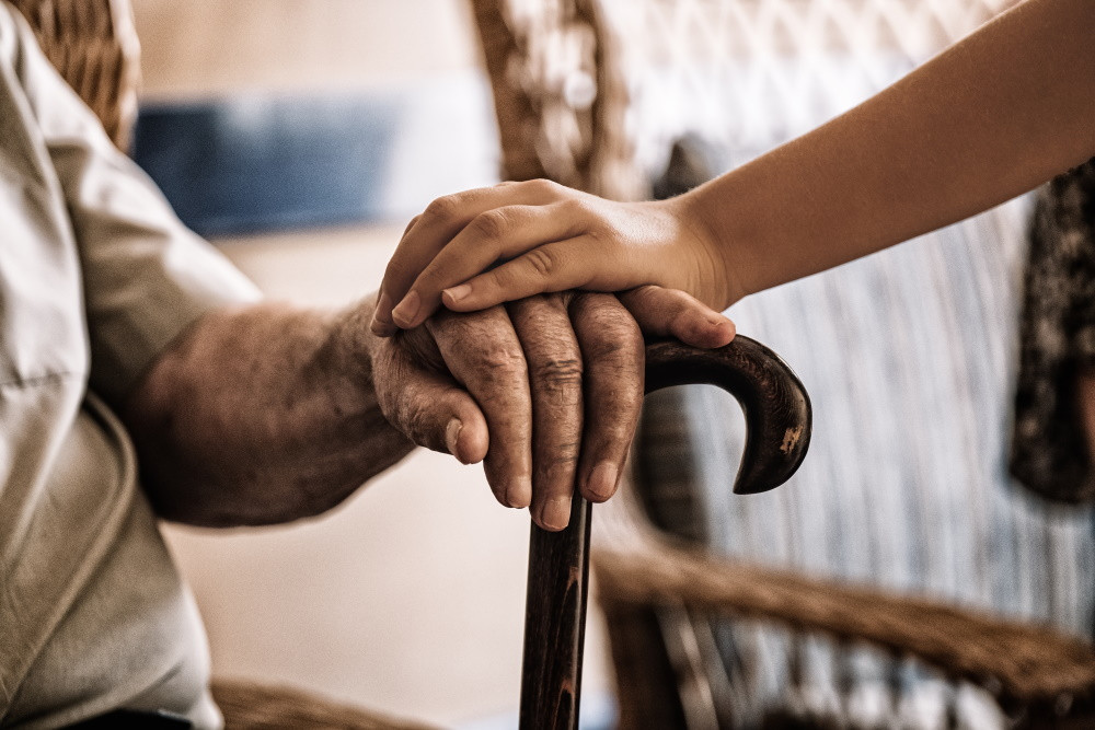 close up of elderly man holding grandchild's hand