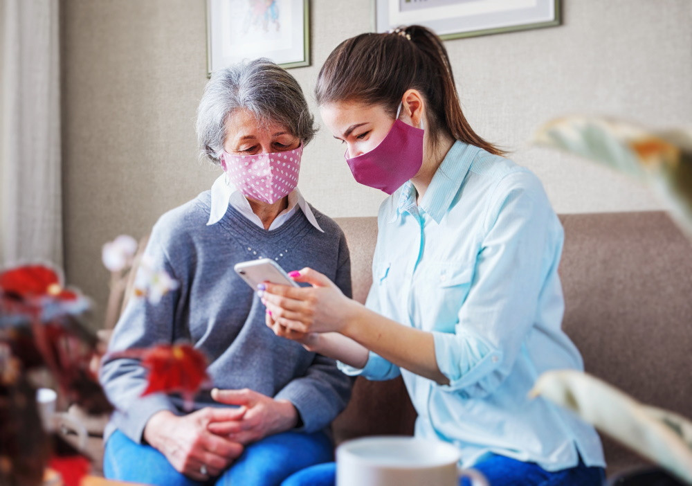 vaccinated senior with granddaughter looking at phone