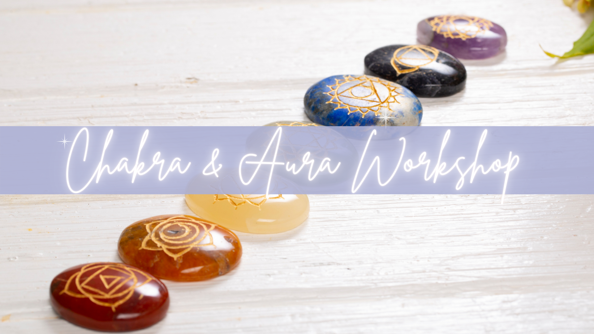 Colored chakra stones on white wood with banner reading Chakra & Aura Workshop.