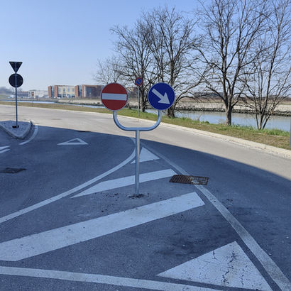 Impianto spartitraffico con segnali di senso vietato e direzione obbligatoria installato su isola di traffico.