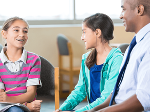 School administrator sitting with two smiling middle school girls, discussing educational programs, symbolizing planning for drone integration in school STEM curriculum.