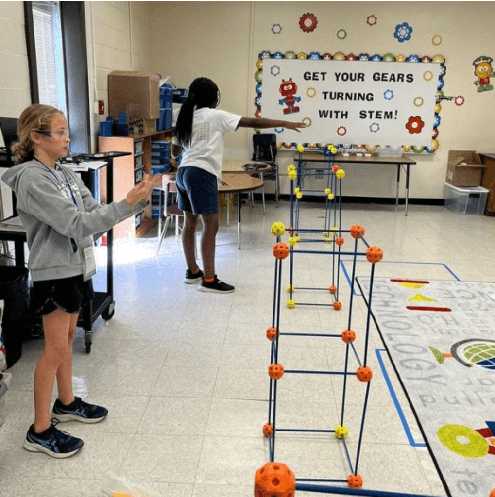 Two students in a STEM classroom building with engineering kits, practicing teamwork and problem-solving in an enrichment program.