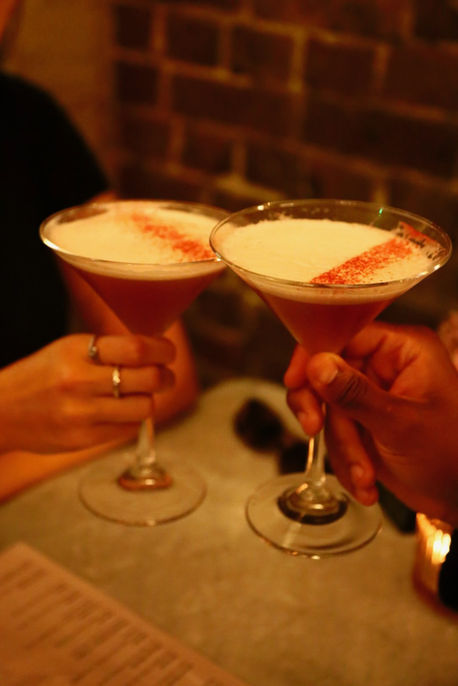 Two people toasting with pink cocktails