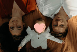 Parents et bébé allongés sur un tapis regardant le photographe