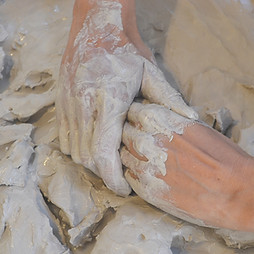 Hands covered in clay during an embodied clay practice session using the Clay Field method