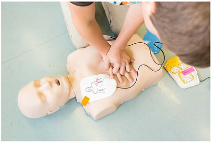 A CPR dummy with AED pads on and a child practicing CPR.