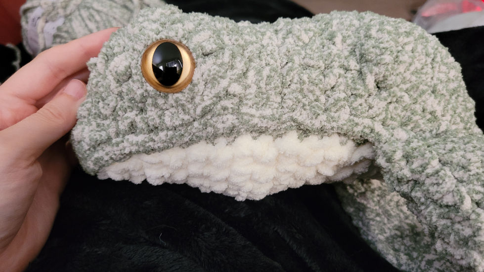 A large crocheted frog plushie.